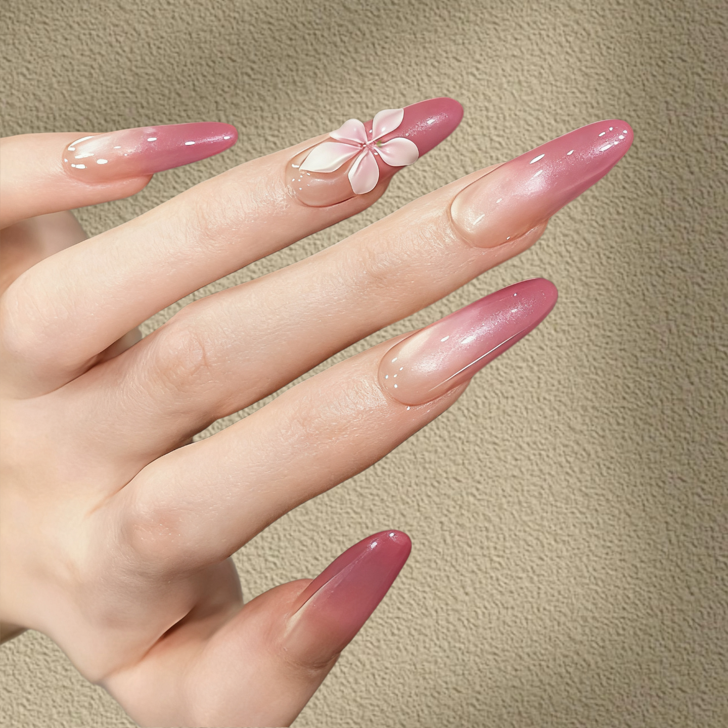 Hand with pink nail polish and a floral design on a beige background