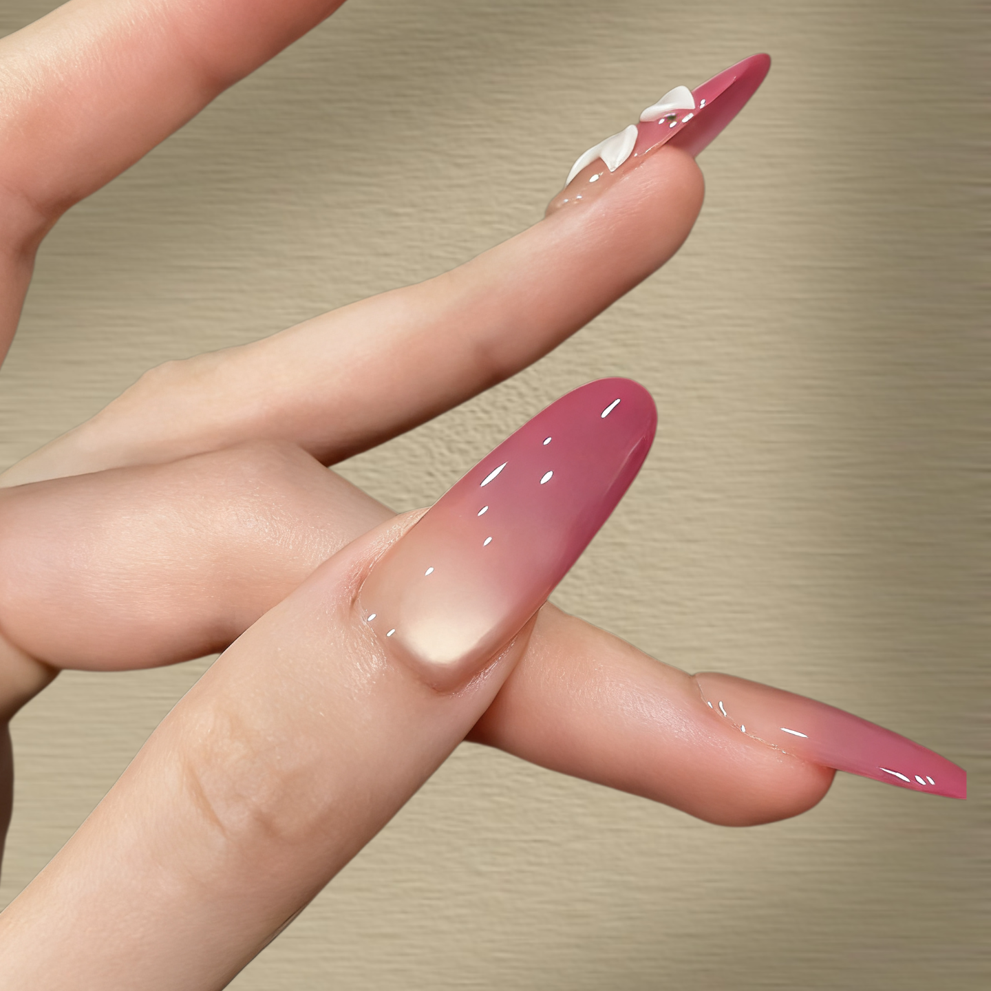 Close-up of a hand with pink nail polish on a beige background