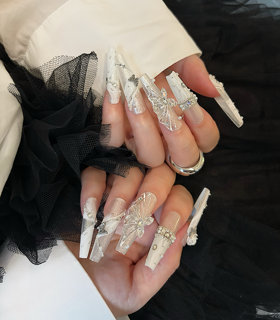 Close-up of hands with decorative nail art against a black and white background