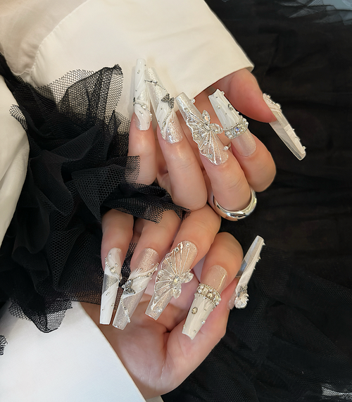 Close-up of hands with decorative nail art against a black and white background