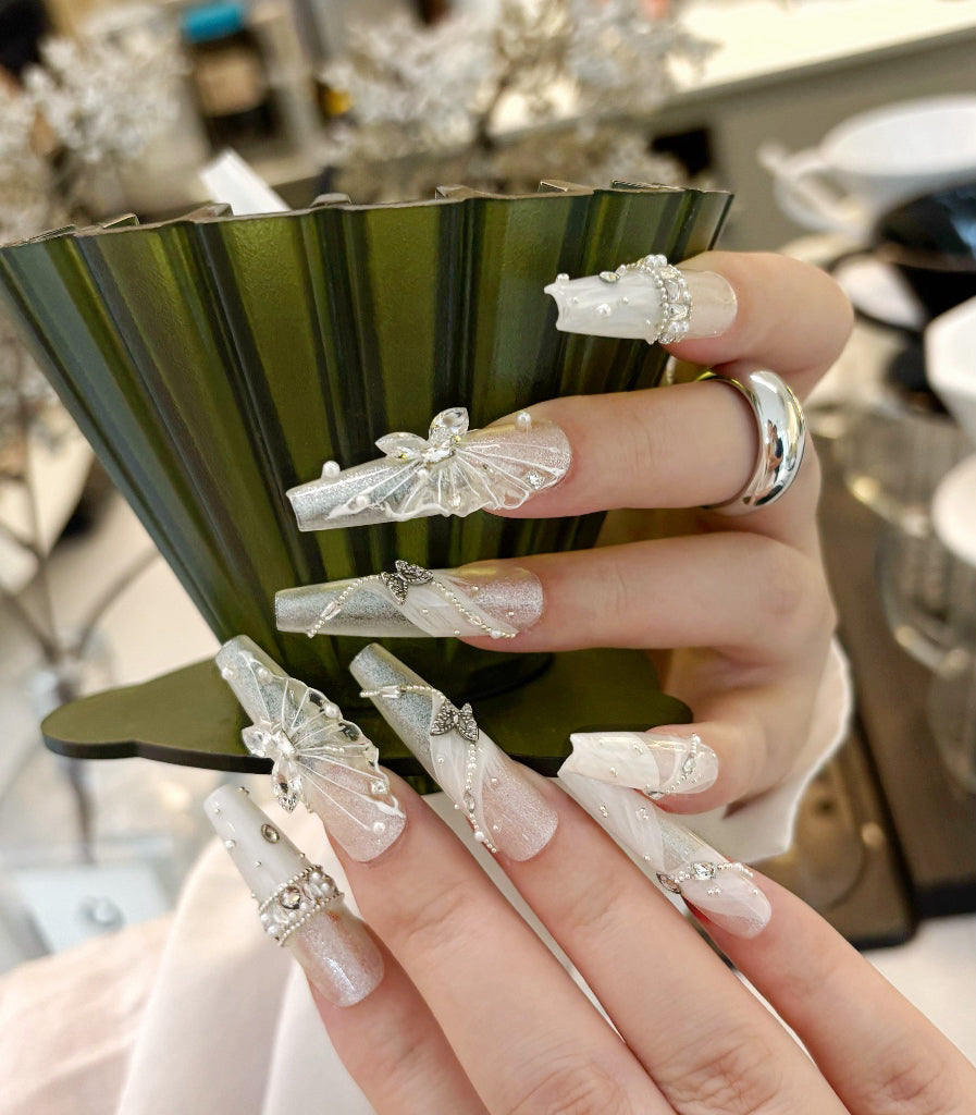 Close-up of a hand with decorative nails holding a green vase.