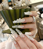 Close-up of a hand with decorative nails holding a green vase.