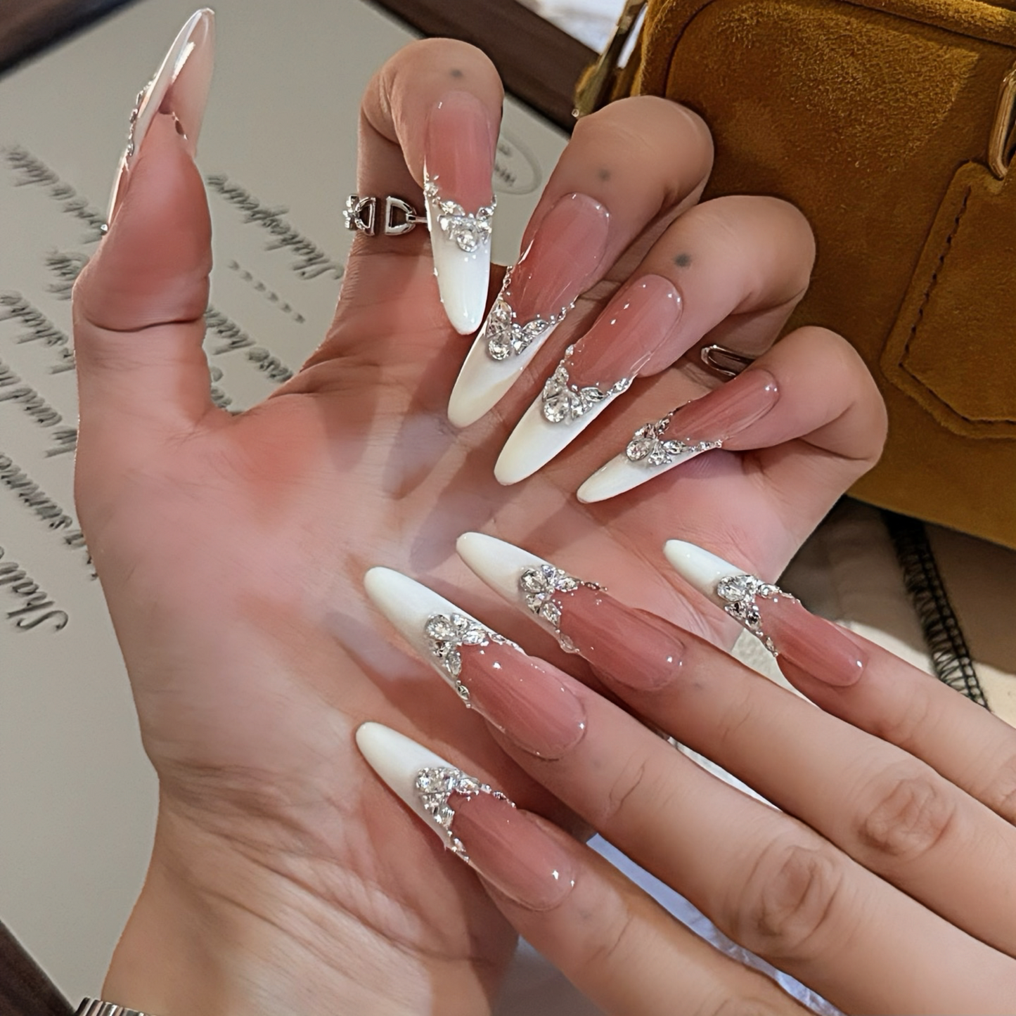 Hand with long, decorated nails held palm-up, with a blurred background.