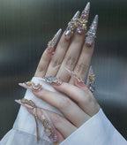 Hand with intricately designed nails and rings against a dark background