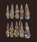 Decorative nail art tips with gemstones and gold accents on a dark background