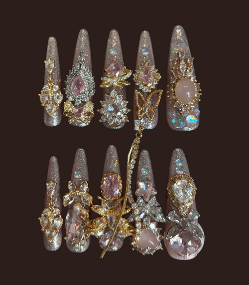Decorative nail art tips with gemstones and gold accents on a dark background