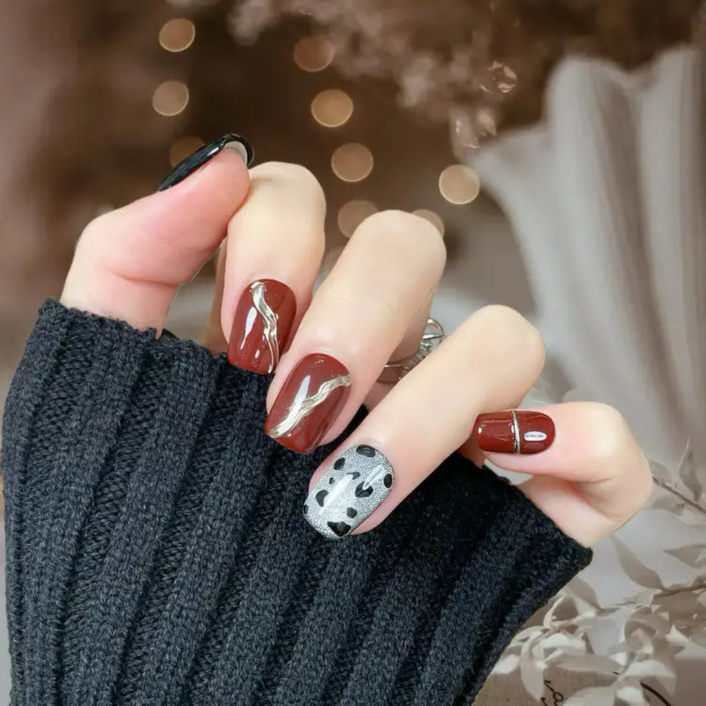 Close-up of a hand with stylish nail art wearing a dark sweater.