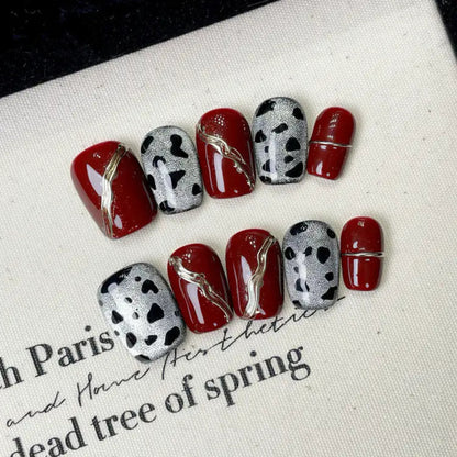 Nails with red and black designs on a white surface with text