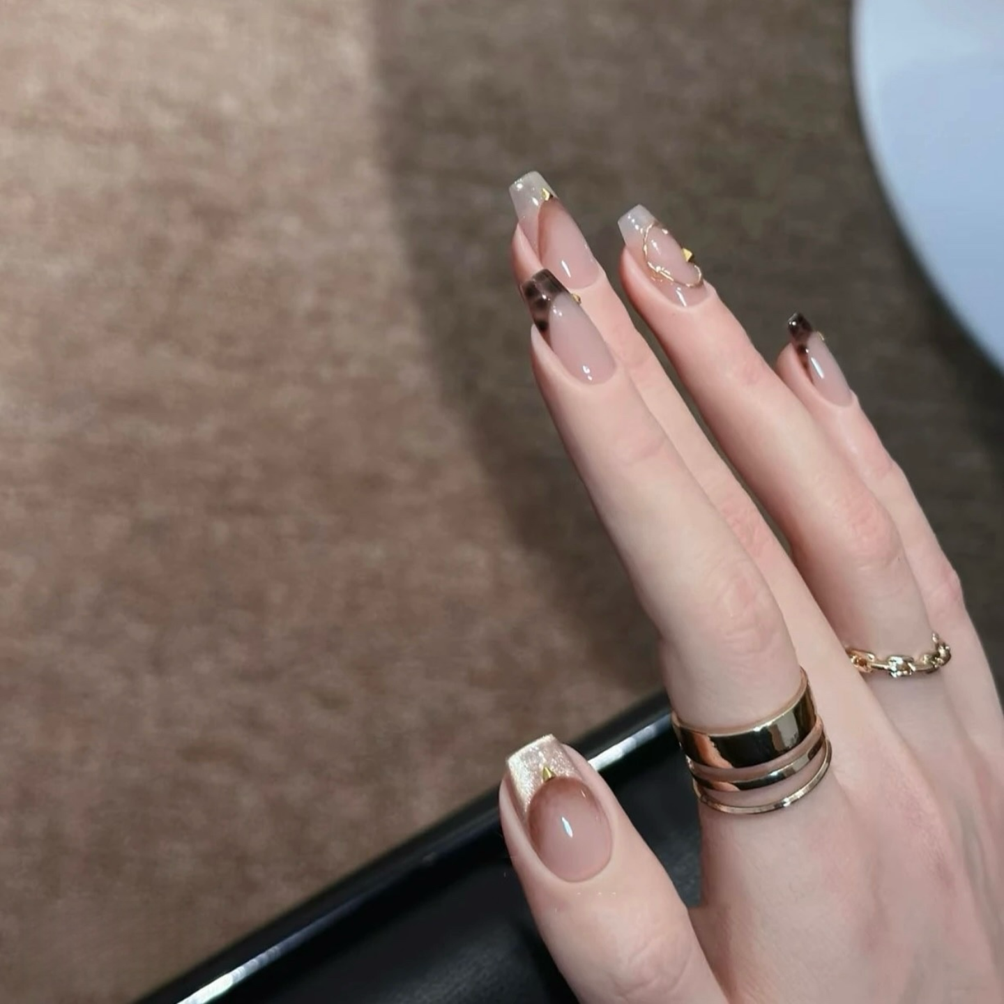Close-up of a hand with decorative nail art on a neutral background