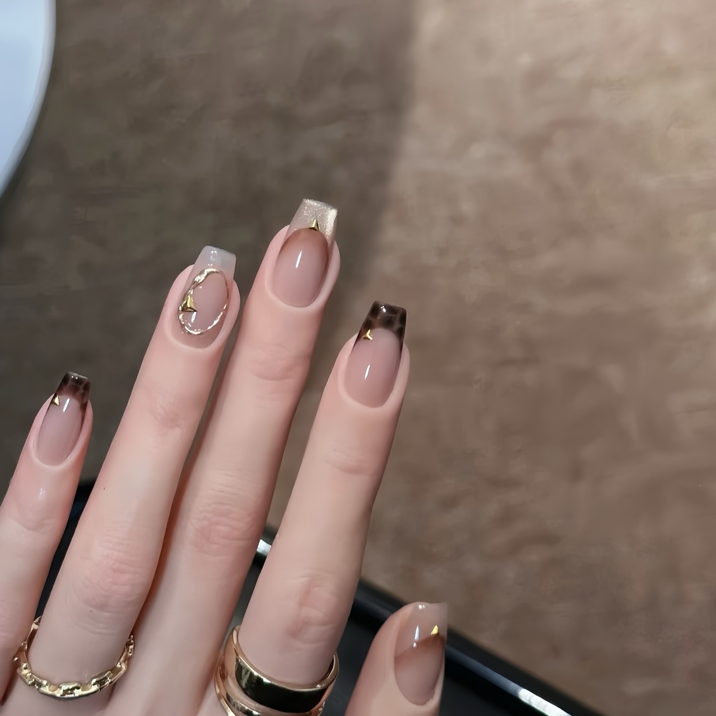 Close-up of a hand with stylish nail art on a neutral background