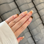 Hand with stylish nail design against a textured gray background
