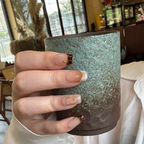 Hand holding a textured ceramic mug with a blurred indoor background