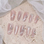 Set of pink press-on nails with rhinestones on a textured surface