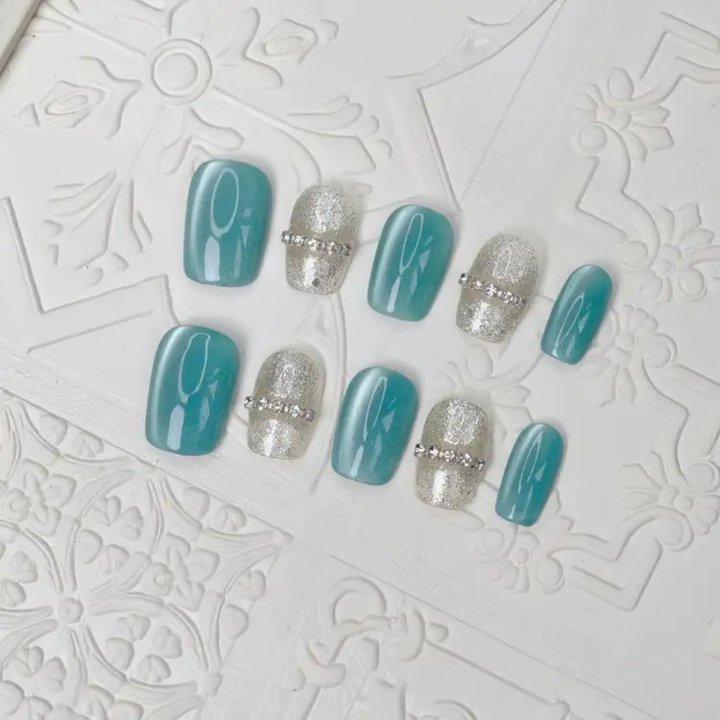 Set of teal and silver nail art designs on a textured white background