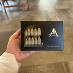 Hand holding a box of decorative nails with 'Able Nail' branding.