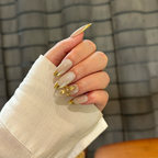 Hand with glittery nails and gold accents against a plaid background