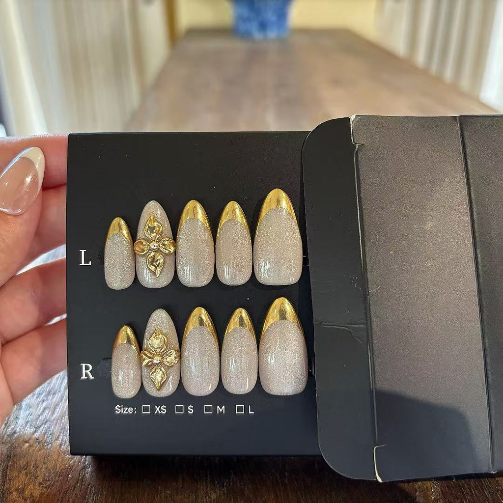 Set of decorative nails with gold accents held by a hand on a wooden surface.