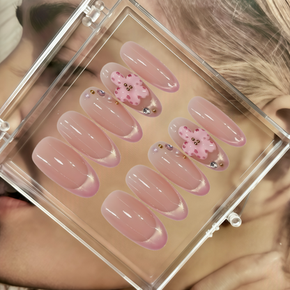 Set of pink press-on nails with decorative elements in a clear case.