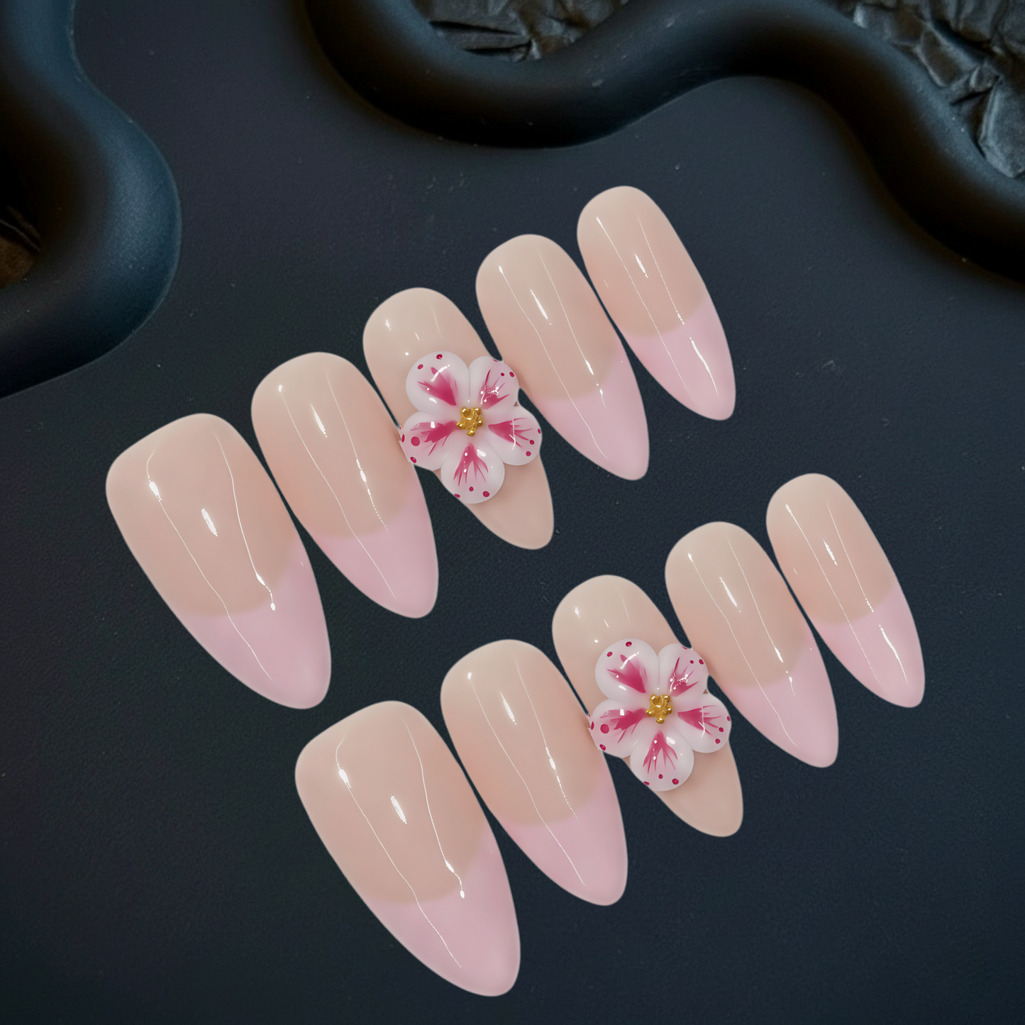 Nail art with pink and beige gradient and floral design on a dark background