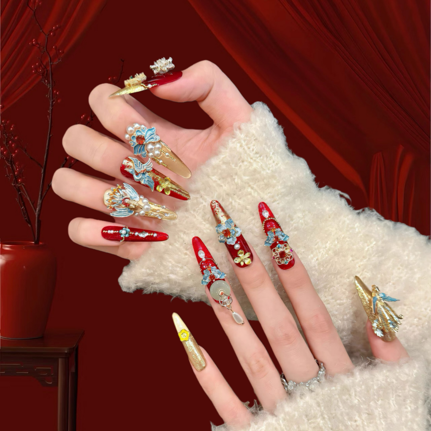 Hand with intricately designed nails against a red background