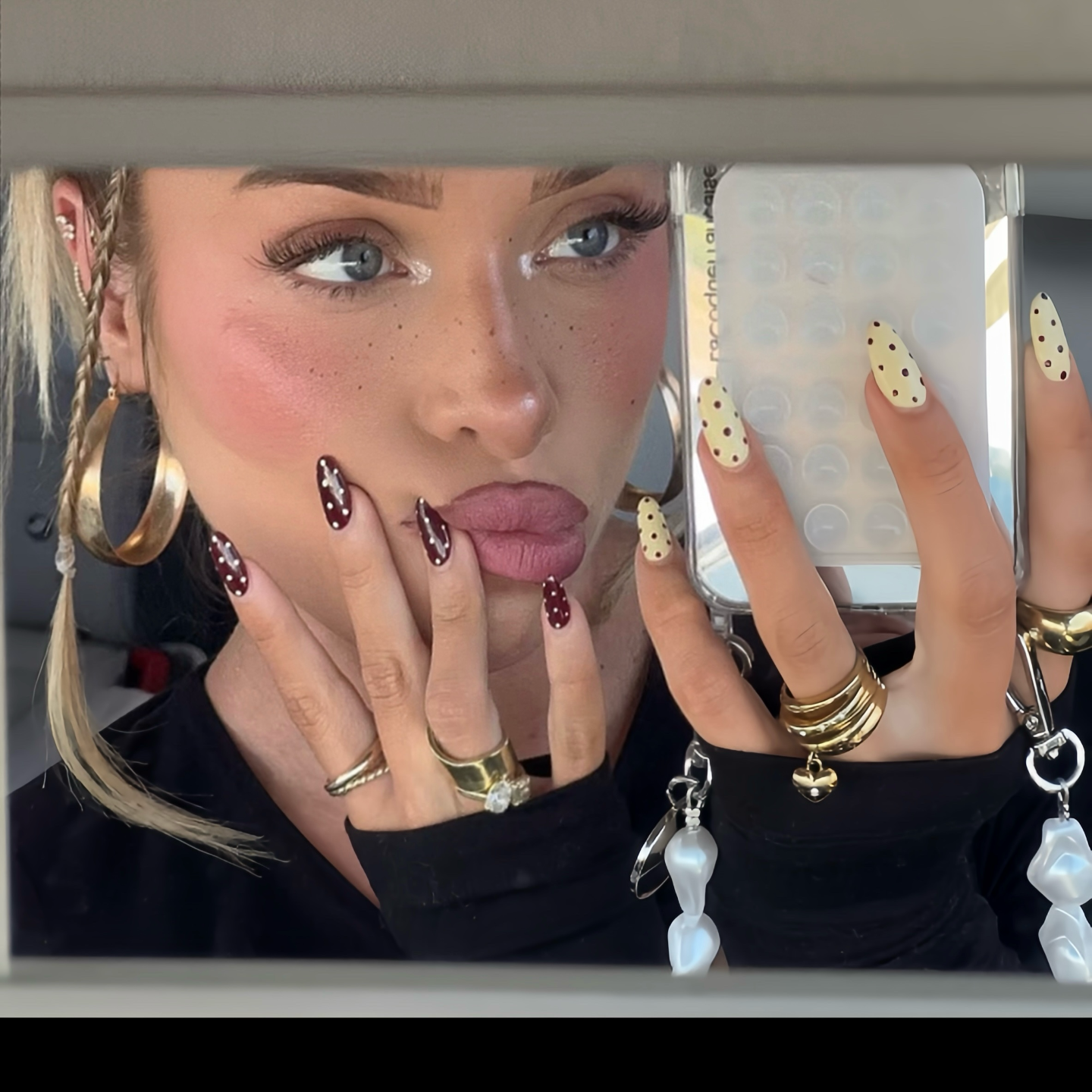 Close-up of a person with stylish nail art and jewelry, including rings and earrings.