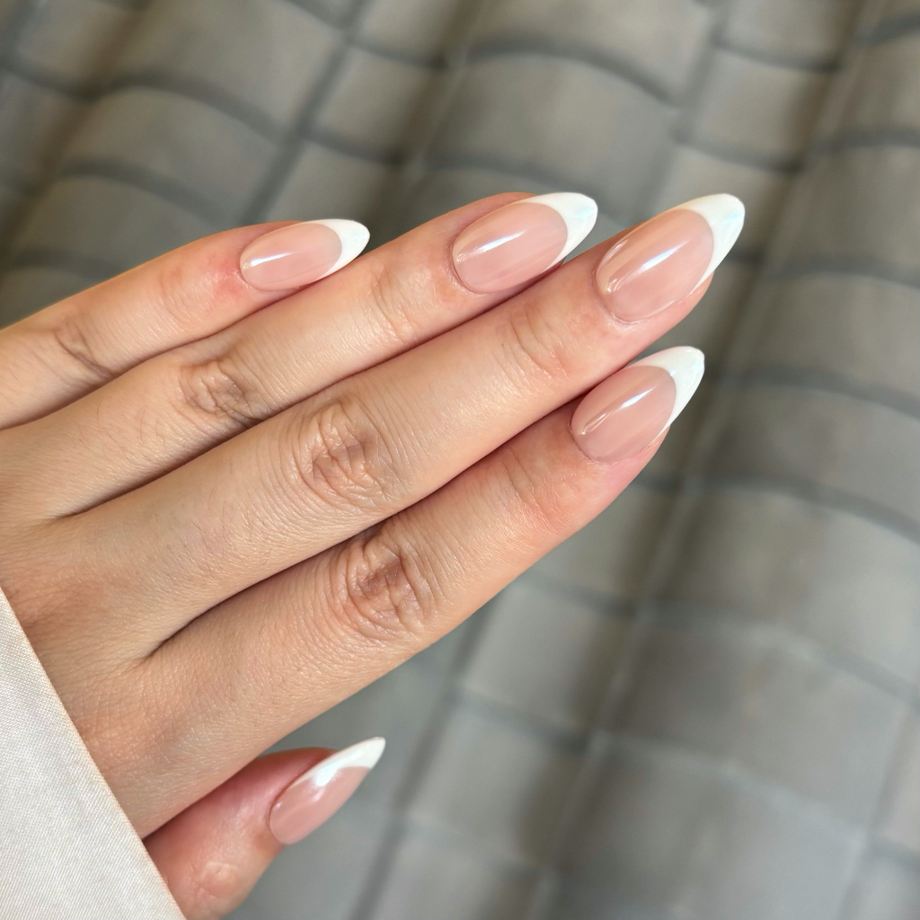 Close-up of a hand with pink and white nail polish against a neutral background