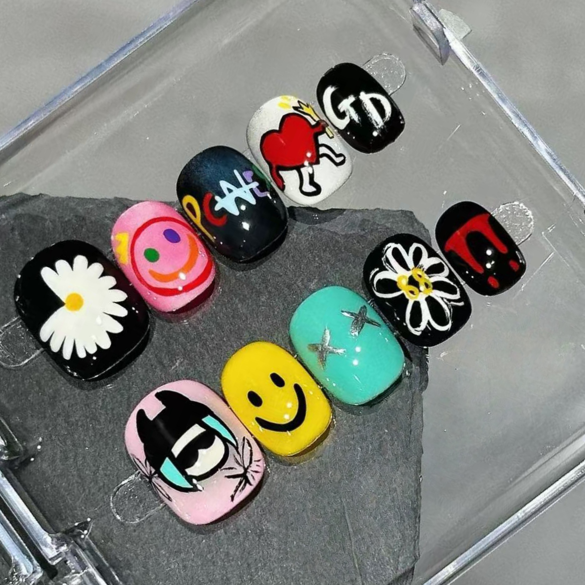 Collection of colorful nail art designs on a gray surface
