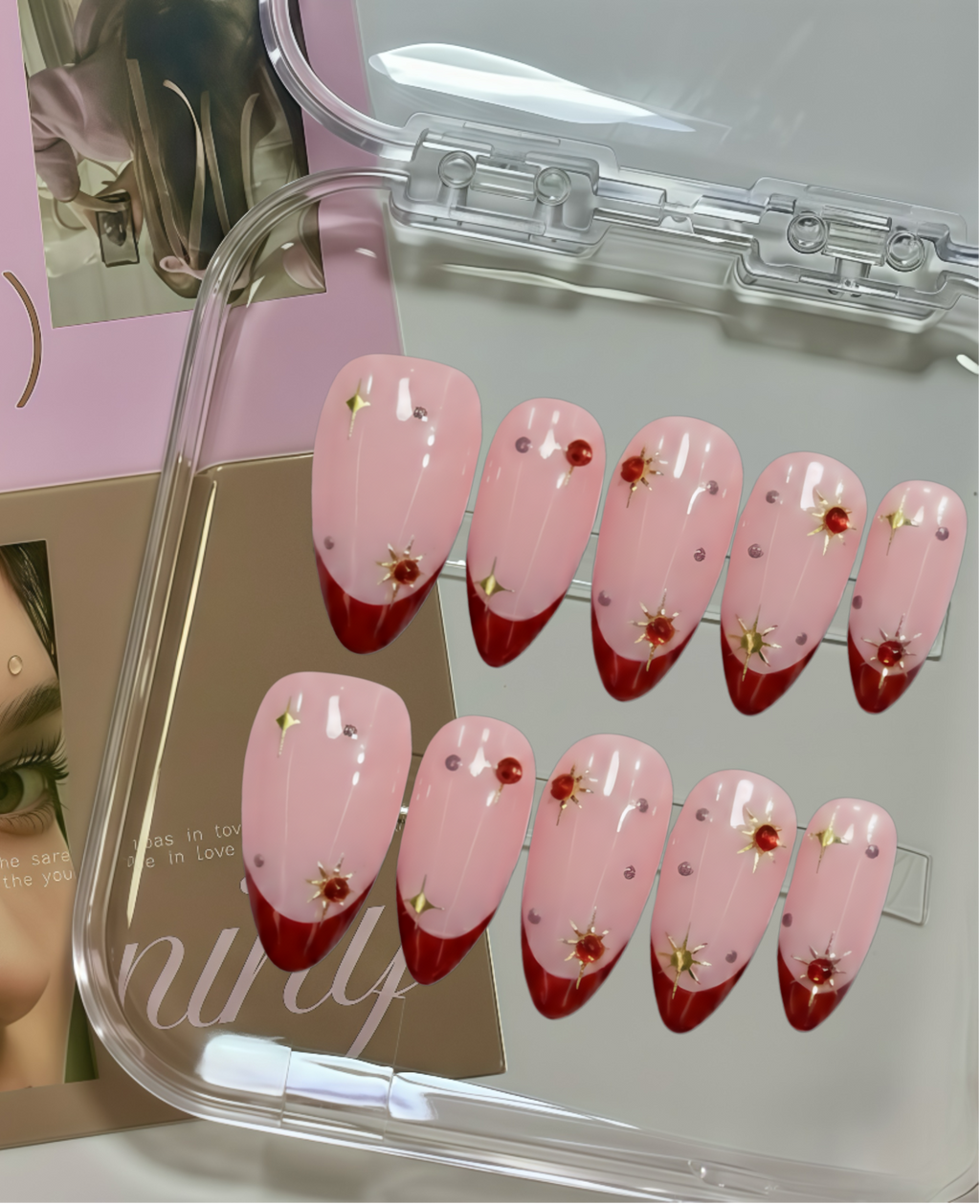 Set of pink and red gradient nail designs with floral decorations in a clear case.