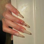 Close-up of a hand with long, pointed nails featuring red and clear design against a neutral background.