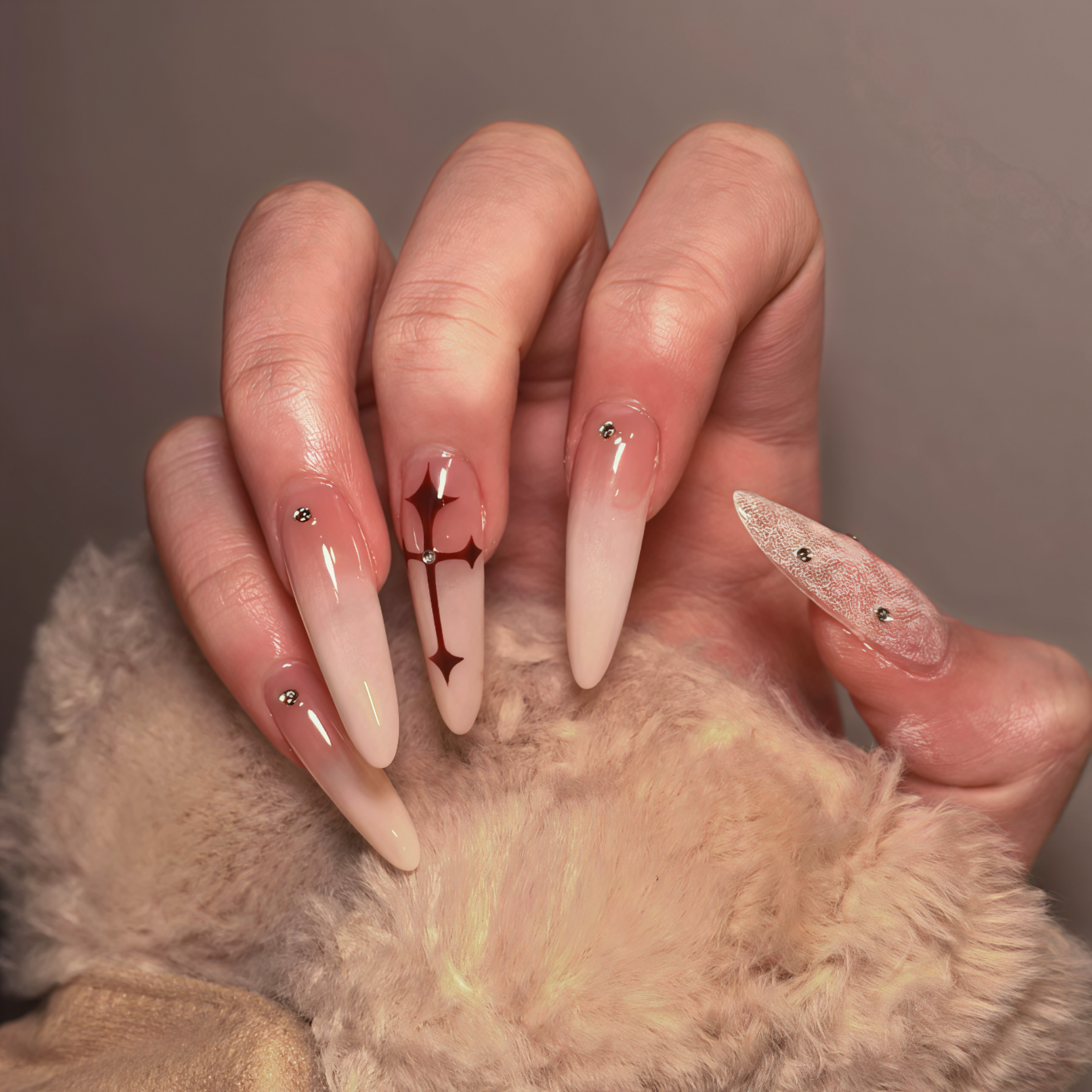 Close-up of a hand with long, decorative nails holding a fluffy beige object.