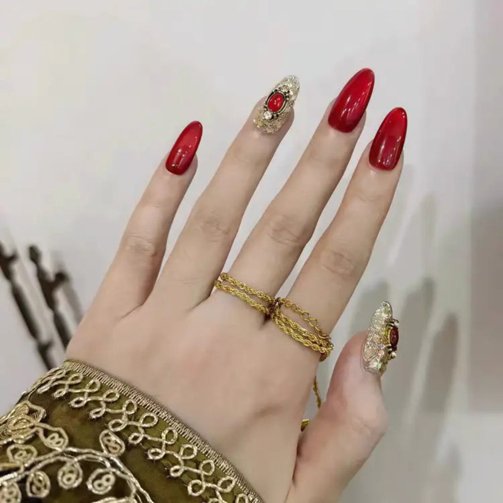 Hand with red nails and gold rings on a neutral background