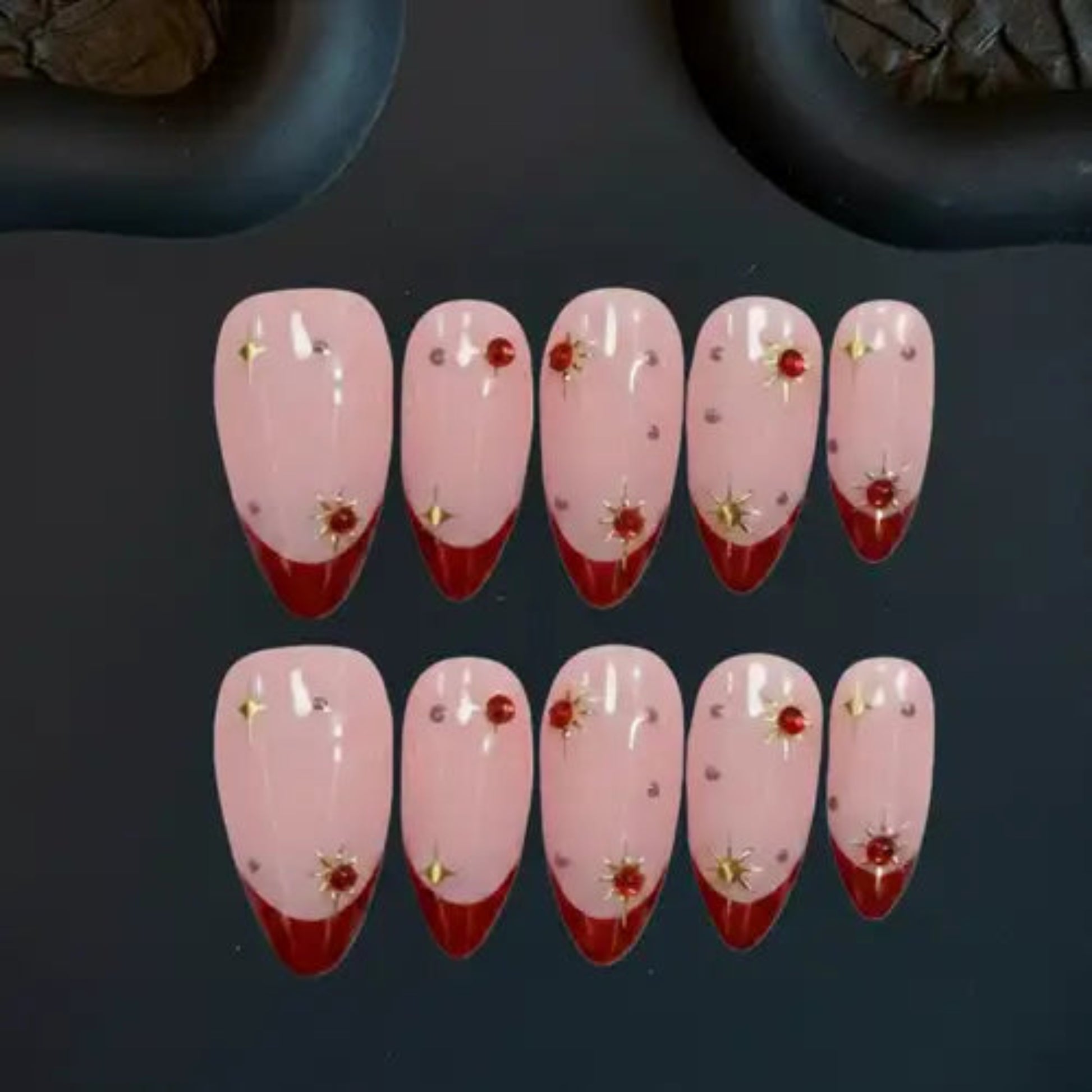 Set of pink and red nail designs with floral decorations on a dark background