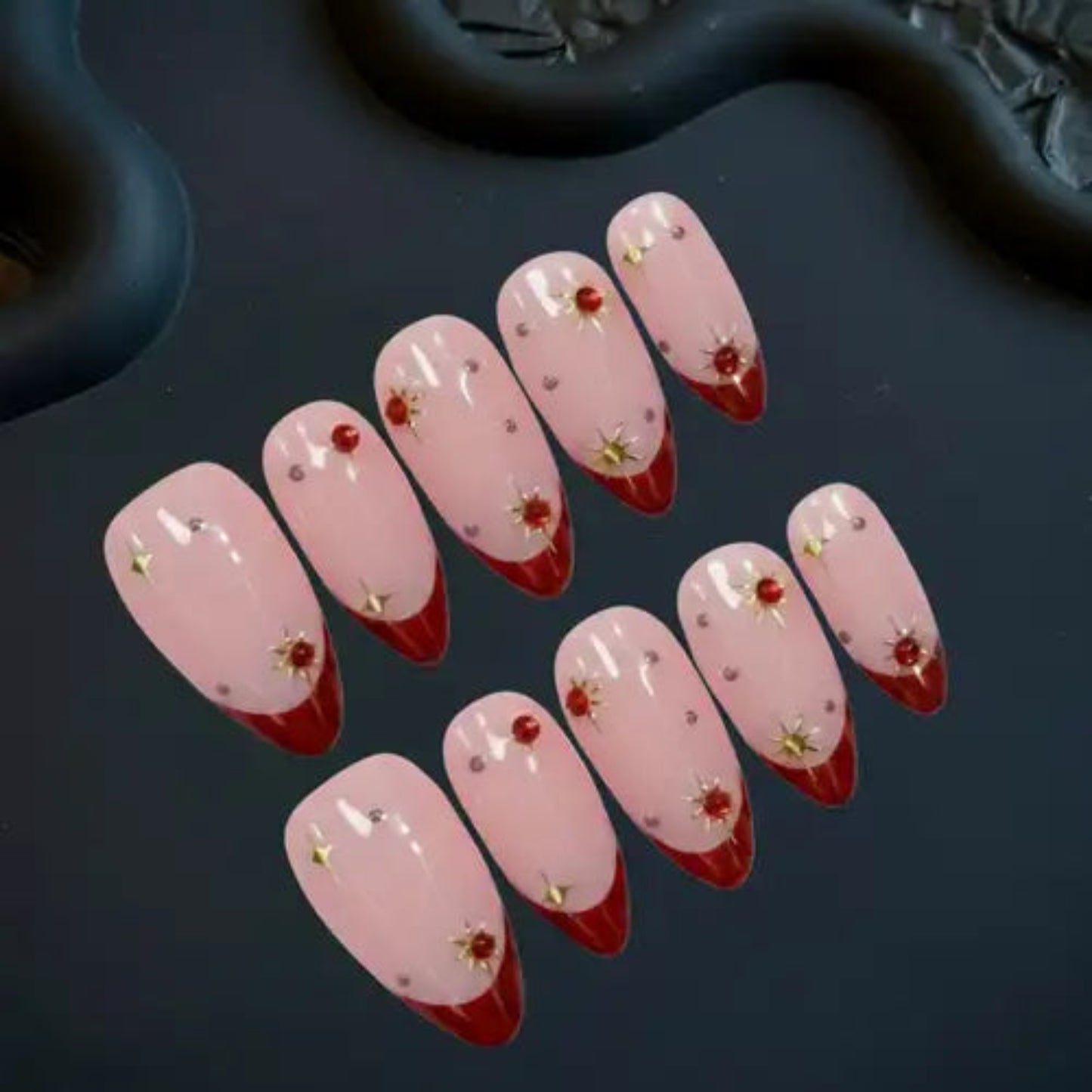 Set of pink and red nail designs with decorative elements on a dark surface