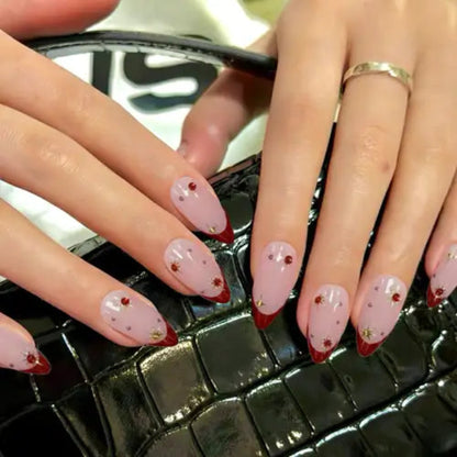 Close-up of hands with pink and red nail design on a textured surface