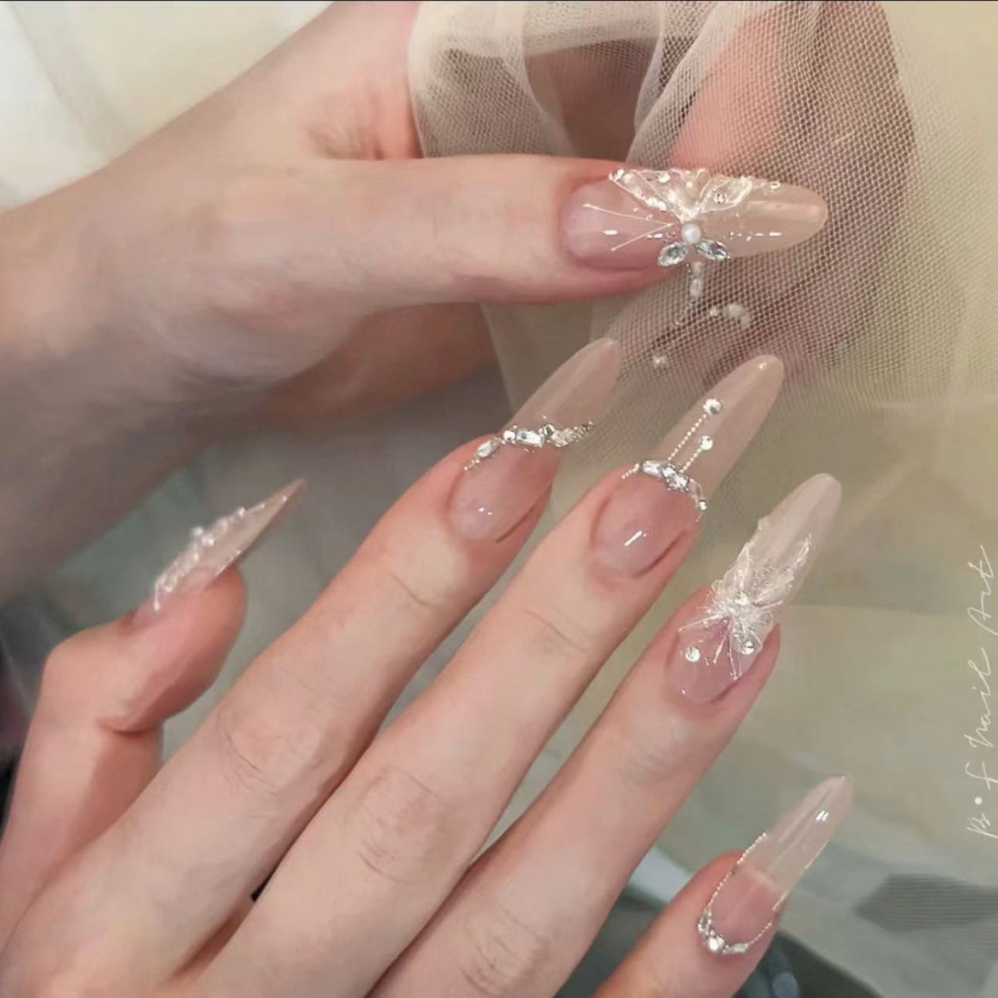 Close-up of hands with decorative nail art featuring transparent and beige designs.