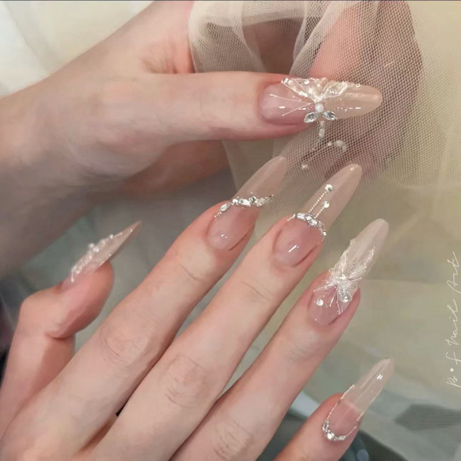 Close-up of hands with decorative nail art featuring transparent and beige designs.