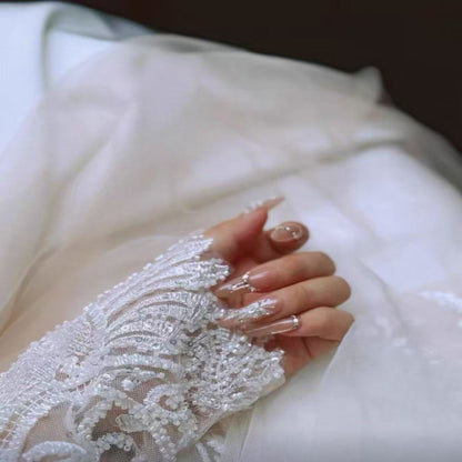 Close-up of a hand wearing a lace glove with intricate detailing.