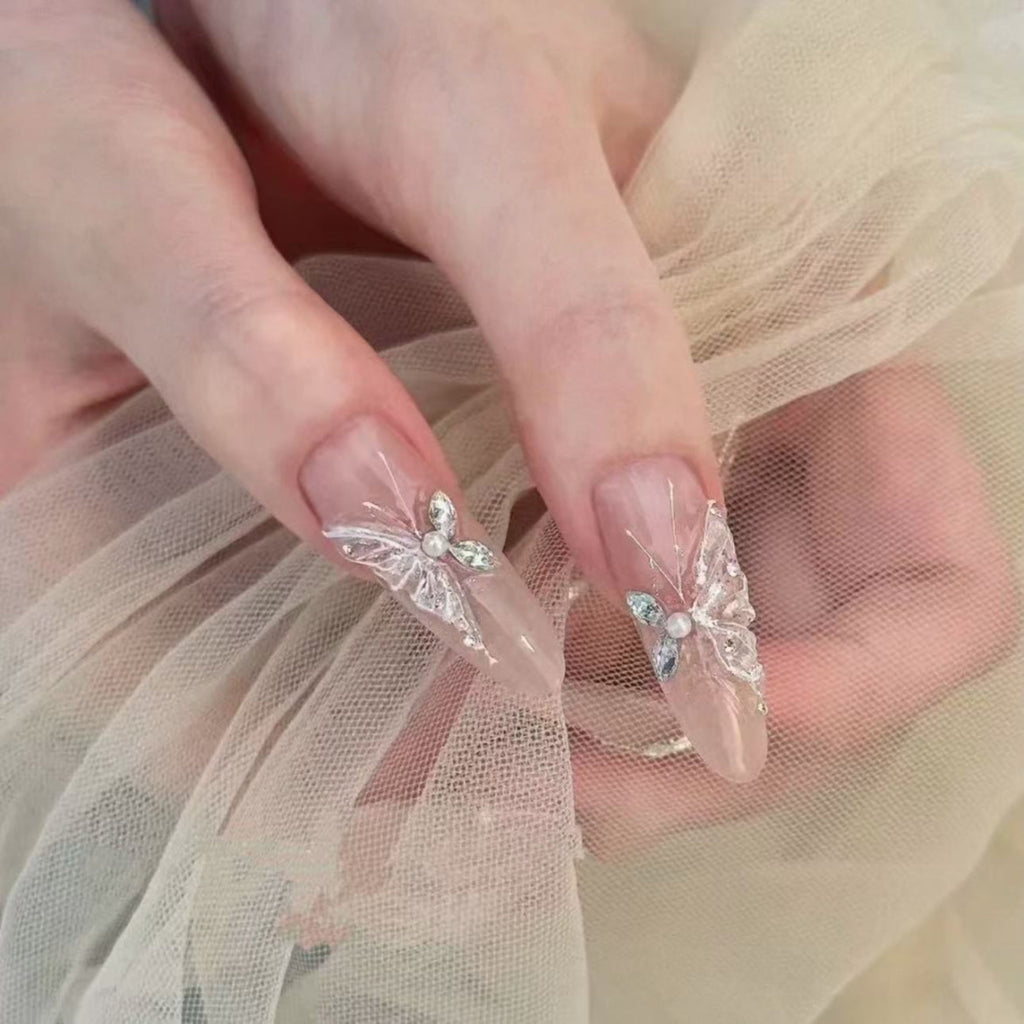 Close-up of hands with butterfly nail art on sheer fabric