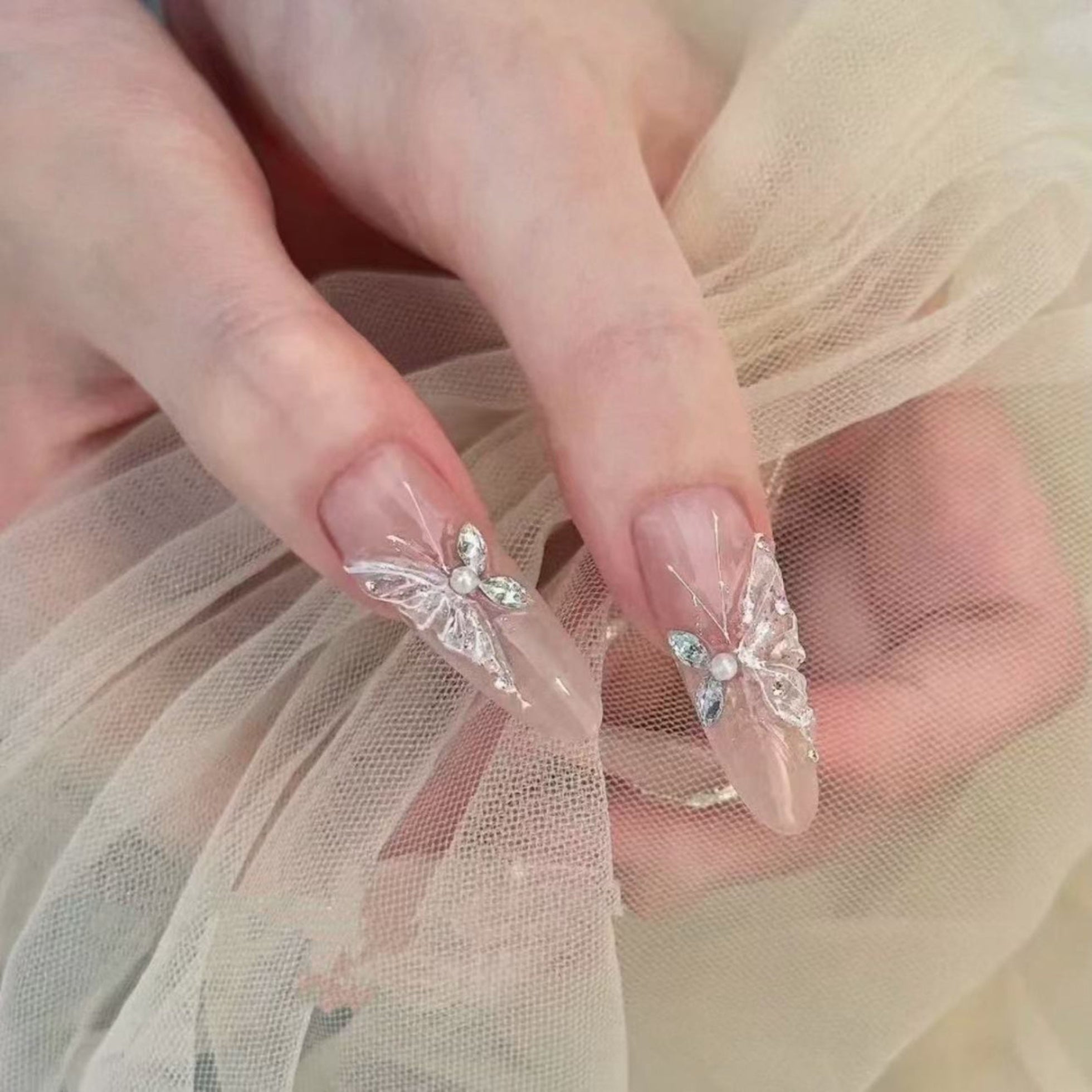 Close-up of hands with butterfly nail art on sheer fabric