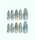 Set of decorative nails with a light blue and silver design on a white background