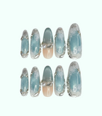Set of decorative nails with a light blue and silver design on a white background