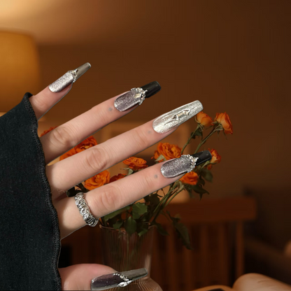 Hand with decorative nails and a ring, holding flowers against a blurred background