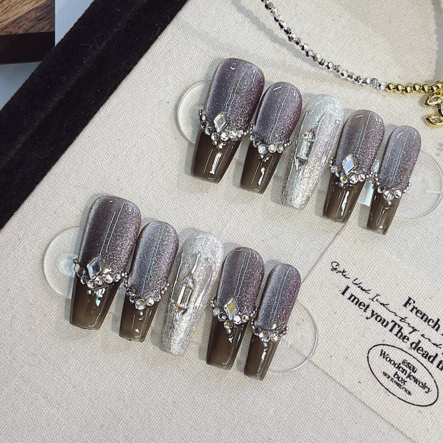 Set of decorative false nails with rhinestones on a textured surface
