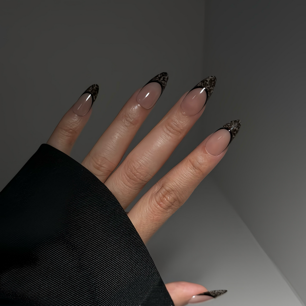 Hand with black and gold nail design against a dark background
