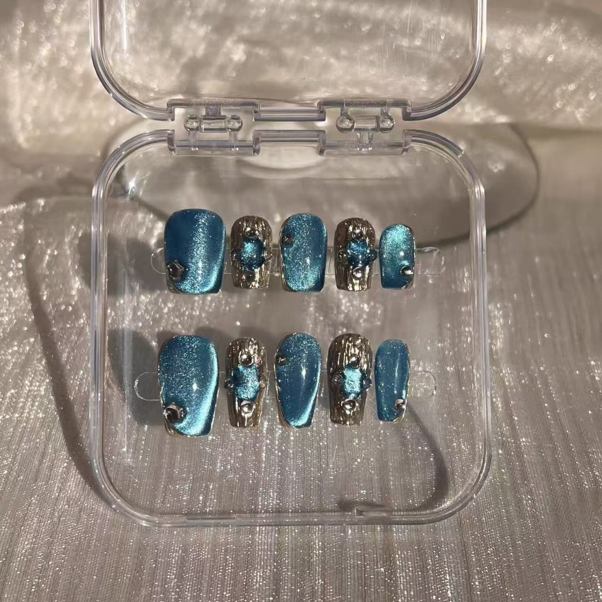 Hand with blue and silver nail design holding a white mug.