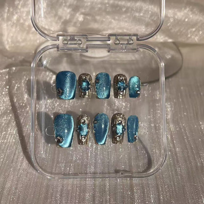 Hand with blue and silver nail design holding a white mug.