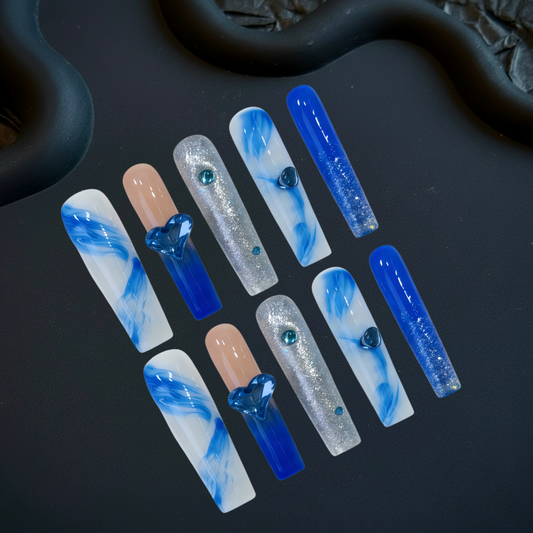 Set of blue and white nail art designs on a dark surface