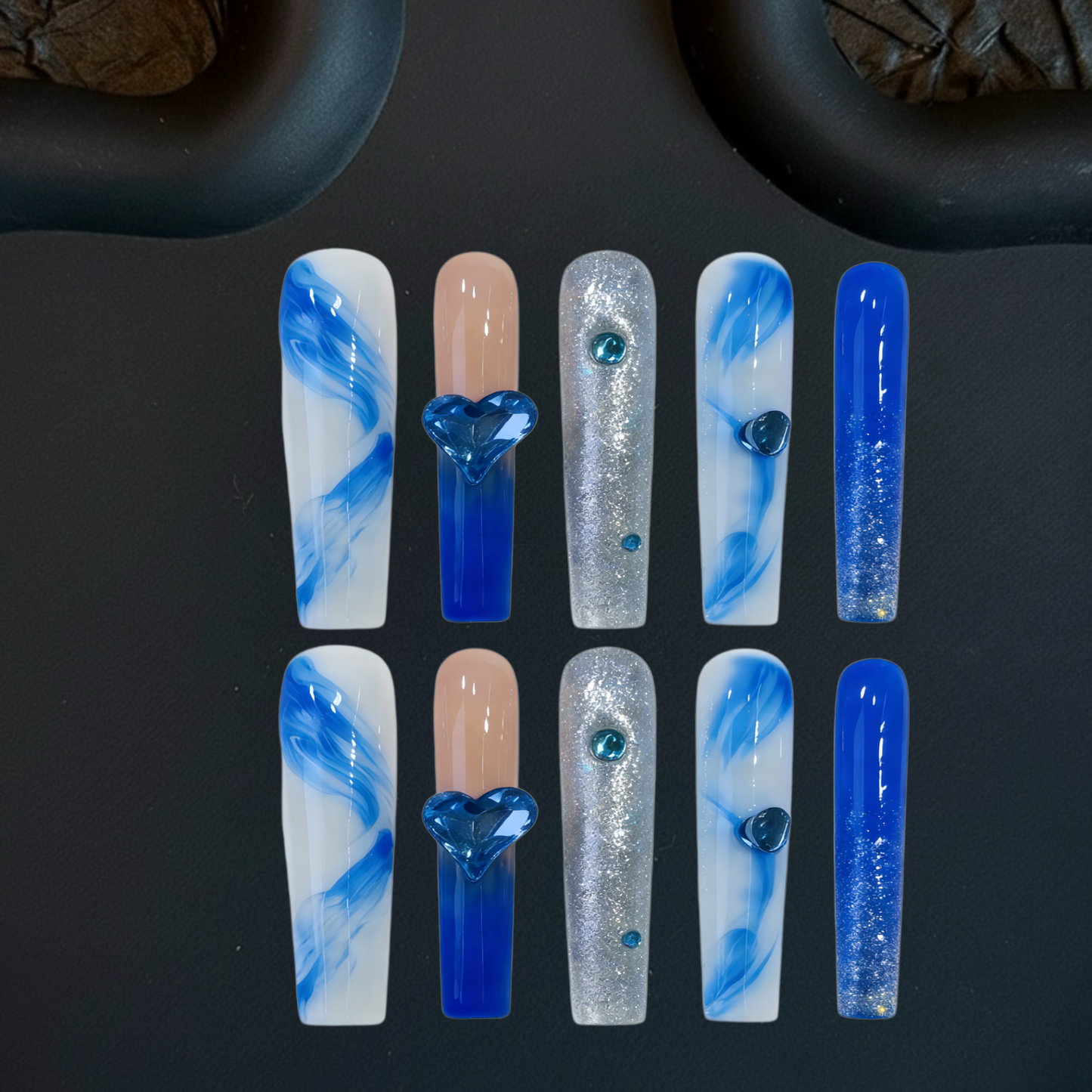 Set of blue, white, and beige nail art designs on a dark surface