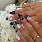 Hand with blue and silver nail art in front of white flowers