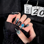 Hand with decorative nail art and rings, featuring a calendar in the background.